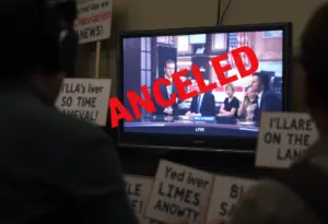 Protest signs against media control and a television showing news coverage