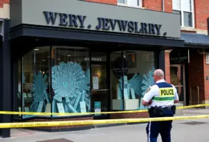 Facade of a jewelry store with broken windows after a burglary shootout.